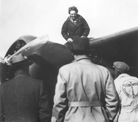 Photo of Amelia Earhart sitting on her plane.